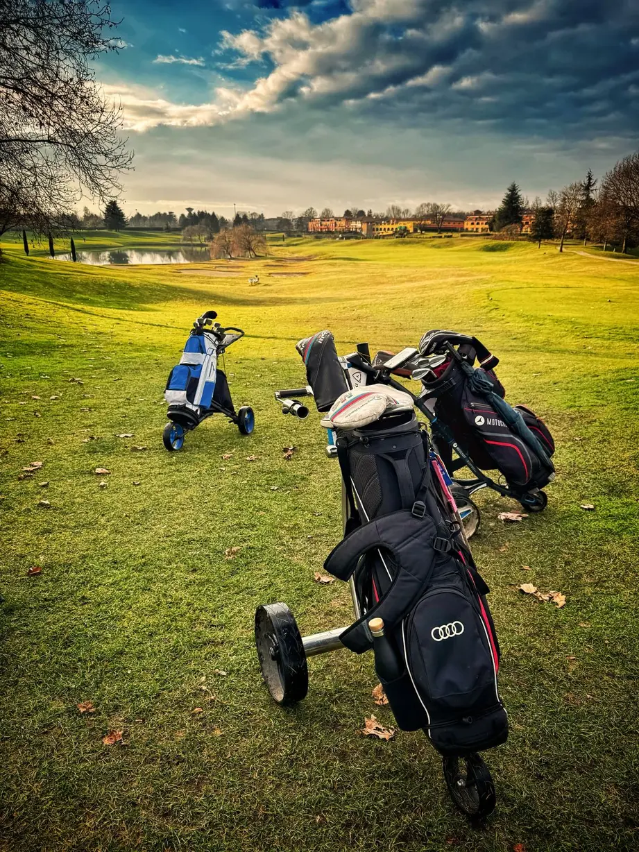 Campo da golf al tramonto con buche e bandiere, metafora di pazienza e equilibrio nella vita