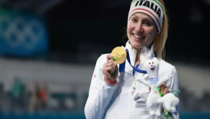 Atleta italiana sorridente mostra la medaglia d'oro olimpica, simbolo di dedizione e lavoro a lungo termine